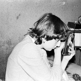Person using early portable hair dryer indoors.