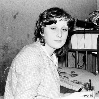 Young woman sitting at sewing table with fabric.