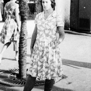 Mid-century street scene with woman in floral dress.