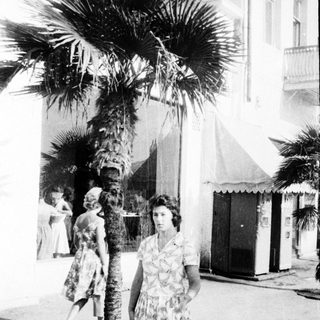 Mid-century street scene with woman in floral dress.