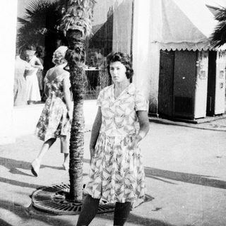 Mid-century street scene with woman in floral dress.