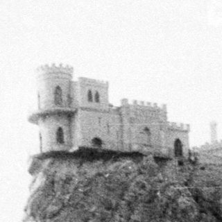 Fortified tower on rocky coastal cliff.