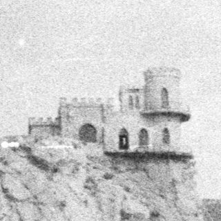 Cliffside castle by coastal waters.