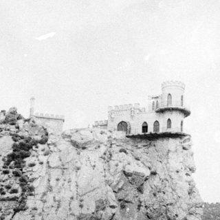 Medieval tower perched on rocky cliffside.