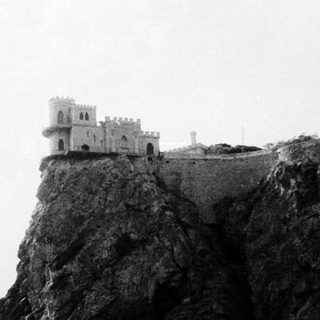 Medieval tower perched on rocky cliff.