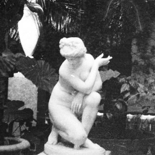 Classic sculptures and palm plants indoors.