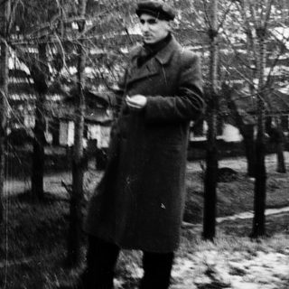 Man in winter coat standing outdoors in snow.