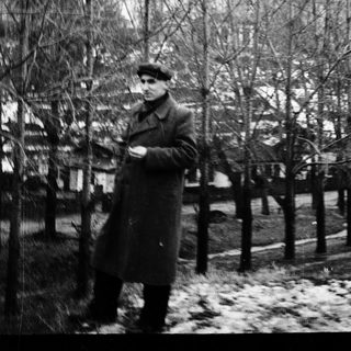 Man in winter coat standing outdoors in snow.
