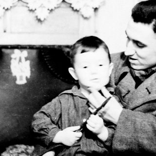 A man teaching a young boy to play piano.