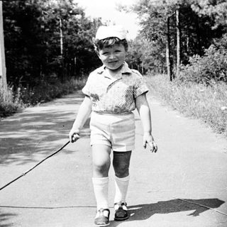 Young boy walking a dog on a paved path.