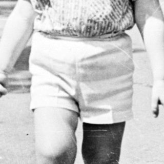Young boy walking a dog on a paved path.