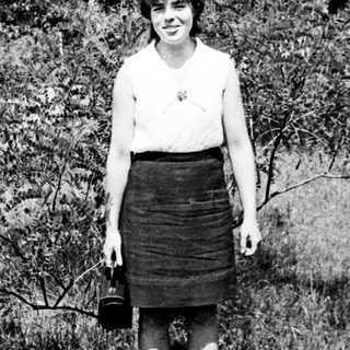 Young woman standing outdoors in vintage skirt and blouse.