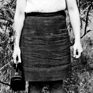 Young woman standing outdoors in vintage skirt and blouse.