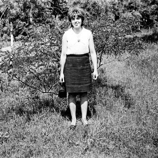 Young woman standing outdoors in vintage skirt and blouse.