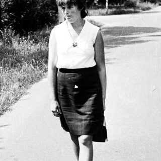 A woman walks alone on a sunny road.