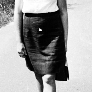 A woman walks alone on a sunny road.