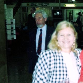 Three women posing indoors near airport baggage claim.