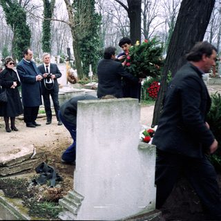 Funeral gathering at a cemetery with mourners.