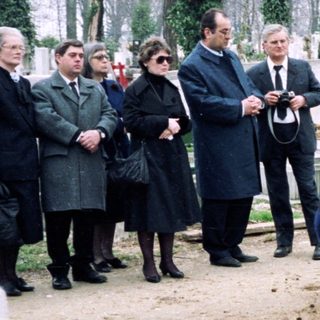 Funeral gathering at a cemetery with mourners.