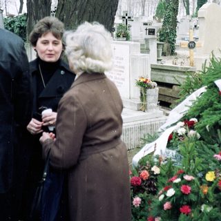 Visitors paying respects at a cemetery grave.