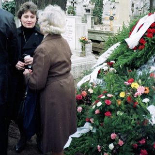 Visitors paying respects at a cemetery grave.