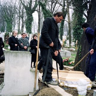 People tending graves in a cemetery.