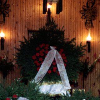Memorial wreaths and flowers in a solemn indoor tribute.