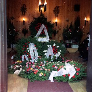 Memorial wreaths and flowers in a solemn indoor tribute.