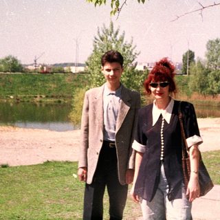 Two people walking outdoors near a lake.