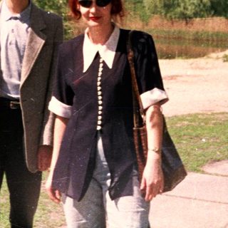 Two people walking outdoors near a lake.