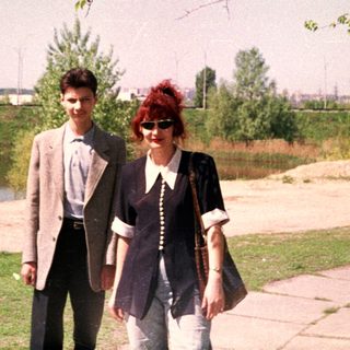 Two people walking outdoors near a lake.