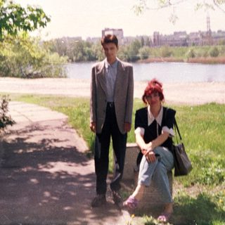 Two people walking and sitting by a river.