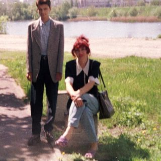 Two people walking and sitting by a river.