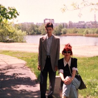 Two people walking by a riverbank in springtime.