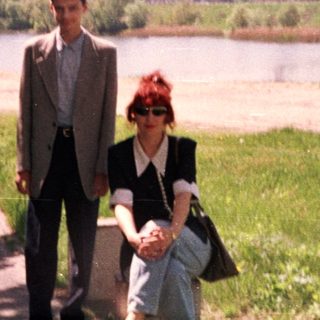 Two people walking by a riverbank in springtime.