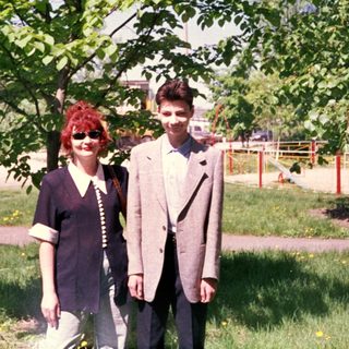 Two people posing outdoors under a tree.