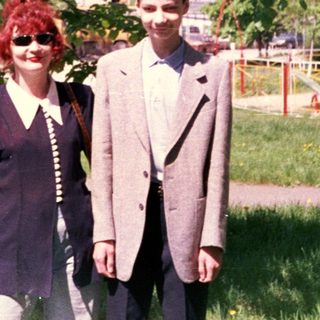 Two people posing outdoors under a tree.