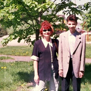 Two people posing outdoors under a tree.