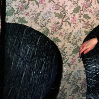 Woman posing in vintage floral-patterned room.