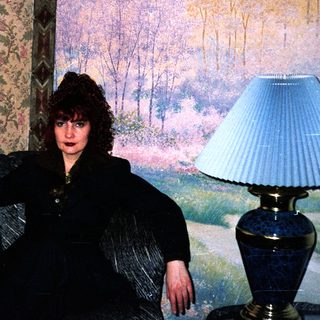 Woman posing in vintage floral-patterned room.
