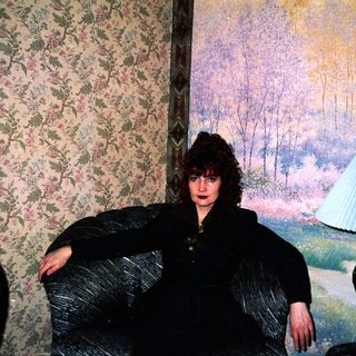 Woman posing in vintage floral-patterned room.