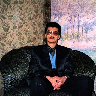 Man in formal attire sitting on armchair.