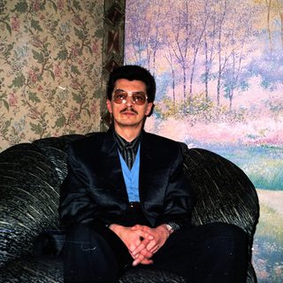 Man in formal attire sitting on armchair.