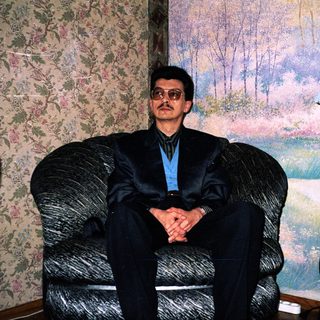 Man in formal attire sitting in armchair indoors.