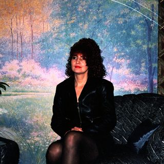 Woman sitting in dimly lit room with large mural.