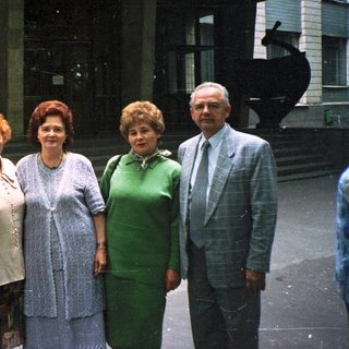 Five adults posing together outdoors in formal attire.