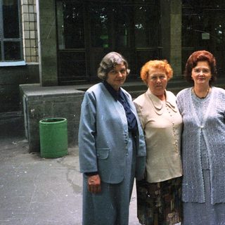 Five adults posing together outdoors in formal attire.
