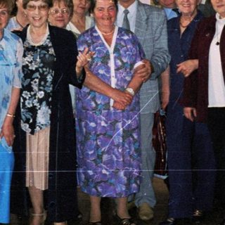 Group posing indoors near mural depicting industrial and agricultural scenes.