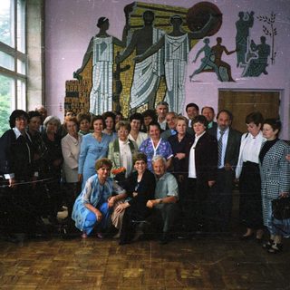 Group of people posing indoors near mural.