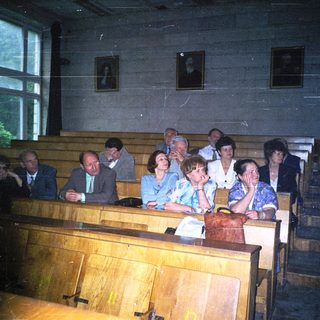 Group of people attending formal indoor gathering in wooden pews.